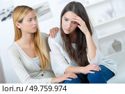 woman comforting crying friend at sofa in home. Стоковое фото, агентство Ingram Publishing / Фотобанк Лори