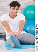 man exercising and stretching towards his toes. Стоковое фото, агентство Ingram Publishing / Фотобанк Лори