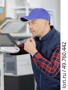 african man fixing photo copier. Стоковое фото, агентство Ingram Publishing / Фотобанк Лори
