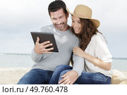 young couple using a digital tablet at seaside town. Стоковое фото, агентство Ingram Publishing / Фотобанк Лори