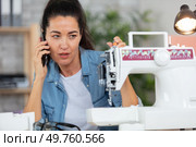 woman with dismantled sewing machine making call on smartphone. Стоковое фото, агентство Ingram Publishing / Фотобанк Лори