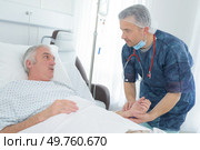 friendly male doctor hold patient hand in hospital room. Стоковое фото, агентство Ingram Publishing / Фотобанк Лори