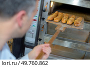 baker getting fresh bread out of the traditional oven. Стоковое фото, агентство Ingram Publishing / Фотобанк Лори