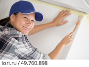 female painting a wall with masking tape and brush. Стоковое фото, агентство Ingram Publishing / Фотобанк Лори