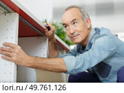 a senior man assembles furniture. Стоковое фото, агентство Ingram Publishing / Фотобанк Лори