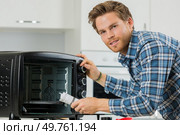 man cleaning up after replacing the filter in a microwave. Стоковое фото, агентство Ingram Publishing / Фотобанк Лори