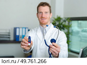 doctor holding forwards a thermometer and stethoscope. Стоковое фото, агентство Ingram Publishing / Фотобанк Лори