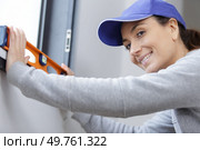 happy woman marks wall with bubble level. Стоковое фото, агентство Ingram Publishing / Фотобанк Лори