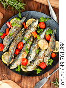 Baked sardine fish with lemon, cherry tomatoes and rosemary on rustic wooden table. Healthy and tasty dinner. Rustic style.. Grilled sardines on a plate with lemon. Стоковое фото, агентство Ingram Publishing / Фотобанк Лори