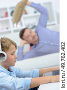 Man poised to throw cushion at young boy on computer. Стоковое фото, агентство Ingram Publishing / Фотобанк Лори