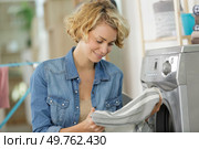 woman checking garment by washing machine. Стоковое фото, агентство Ingram Publishing / Фотобанк Лори