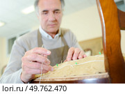 portrait of peaceful senior cabinetmaker repairing an old chair. Стоковое фото, агентство Ingram Publishing / Фотобанк Лори