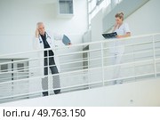 doctor nd nurse in hospital corridor resting against balcony. Стоковое фото, агентство Ingram Publishing / Фотобанк Лори