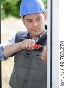 mature worker fastens the handle to a plastic window. Стоковое фото, агентство Ingram Publishing / Фотобанк Лори