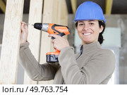 smiling young professional woman using cordless screwdriver on wood. Стоковое фото, агентство Ingram Publishing / Фотобанк Лори