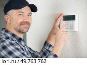 male technician programming electronic keypad. Стоковое фото, агентство Ingram Publishing / Фотобанк Лори