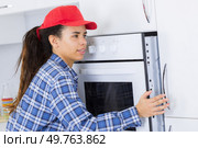 portrait of a female inserting a fitted oven. Стоковое фото, агентство Ingram Publishing / Фотобанк Лори
