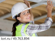 young woman electrician in workwear with screwdriver on ladder. Стоковое фото, агентство Ingram Publishing / Фотобанк Лори