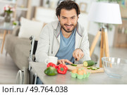 disabled young man in wheelchair preparing dinner in the kitchen. Стоковое фото, агентство Ingram Publishing / Фотобанк Лори