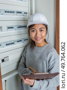 woman holding clipboard next to fuseboard. Стоковое фото, агентство Ingram Publishing / Фотобанк Лори