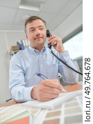 Man on telephone, colour charts in front of him. Стоковое фото, агентство Ingram Publishing / Фотобанк Лори