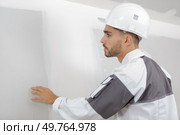 male builder checking the quality of the wall after plastering. Стоковое фото, агентство Ingram Publishing / Фотобанк Лори