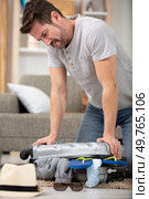 man tries to close a suitcase. Стоковое фото, агентство Ingram Publishing / Фотобанк Лори