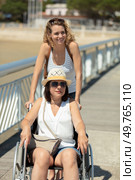lady pushes female friend in wheelchair while on summer holiday. Стоковое фото, агентство Ingram Publishing / Фотобанк Лори