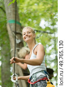 daring woman wearing harness strapped to zip wire in trees. Стоковое фото, агентство Ingram Publishing / Фотобанк Лори