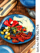 Greek appetizer of sun-dried tomatoes, black and green olives and stuffed cheese with marinated red peppers on rustic wooden table.. Tasty antipasto mix. Стоковое фото, агентство Ingram Publishing / Фотобанк Лори