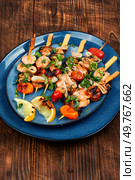 Grilled squid, fried mussels and shrimps, prawns on skewers on rustic wooden table.. Appetizing seafood kebabs. Стоковое фото, агентство Ingram Publishing / Фотобанк Лори