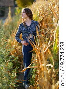 A stylish young woman poses gracefully amidst a lush cornfield, beautifully showcasing a harmonious blend of modern fashion and the natural beauty of the countryside surrounding her. A Fashionable Young Woman Posing Gracefully in a Relaxed Rustic Cornfield Setting. Стоковое фото, агентство Ingram Publishing / Фотобанк Лори