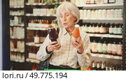 Mature woman chooses natural fruit juice in a store with organic products. European senior woman buys juices in an eco supermarket. Стоковое видео, видеограф Яков Филимонов / Фотобанк Лори