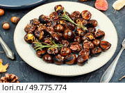 Cracked roasted chestnuts, roasted chestnuts some chestnuts split open , garnished with fresh rosemary, styled with autumn leaves.. Warm roasted chestnuts served on a plate. Стоковое фото, агентство Ingram Publishing / Фотобанк Лори