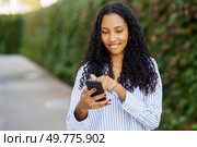 A cheerful young woman is happily enjoying the experience of using her smartphone in a lush outdoor setting, showcasing the essence of modern connectivity and effective communication in todays world. A young woman happily engages with her smartphone in the outdoors, surrounded by nature. Стоковое фото, агентство Ingram Publishing / Фотобанк Лори