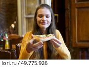 A young woman radiates pure joy as she holds up a cheesy slice of delicious pizza in a cozy restaurant, which has been thoughtfully designed to provide a relaxing atmosphere for all diners to enjoy. Joyful Young Woman Happily Enjoying a Deliciously Savory Slice of Pizza in a Cozy Restaurant Setting. Стоковое фото, агентство Ingram Publishing / Фотобанк Лори