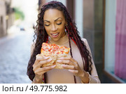 A joyful woman, full of energy and happiness, indulges in a delicious slice of pizza as she strolls down a charming city street, perfectly showcasing the delightful bliss of enjoying street food. A Delighted Woman is Enjoying a Tasty Slice of Pizza in a Beautiful Scenic Urban Setting. Стоковое фото, агентство Ingram Publishing / Фотобанк Лори