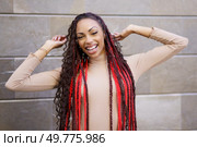 A joyful young woman with long braided hair poses playfully in a lively urban setting. Her unique fashion and infectious happiness captivate and draw smiles from everyone around her. A Stylish Young Woman with Long, Beautifully Braided Hair in a Vibrant Urban Setting. Стоковое фото, агентство Ingram Publishing / Фотобанк Лори