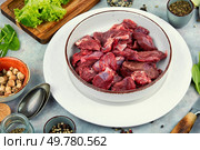 Raw venison slices arranged with fresh fragrant herbs. Food photography.. Sliced raw venison deer meat for a stew. Стоковое фото, агентство Ingram Publishing / Фотобанк Лори