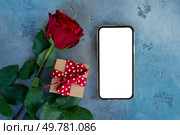Crimson red rose flower with gift box, mock up with modern phone, Valentine’s Day background. Crimson red rose flowers. Стоковое фото, агентство Ingram Publishing / Фотобанк Лори