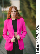 A stylish young woman confidently poses in a vibrant pink blazer and trendy black crop top, set against a beautifully blurred outdoor background that highlights her flair for modern fashion. A FashionForward Young Woman is Donning a Vibrant Pink Blazer While Posing Outdoors. Стоковое фото, агентство Ingram Publishing / Фотобанк Лори