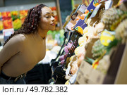 In a bustling and vibrant market, a woman joyfully admires the wide variety of fresh fruits available to her, showcasing the immense pleasure of healthy eating and the simple joy of grocery shopping. A woman is happily enjoying a variety of fresh, colorful fruits at the local market today. Стоковое фото, агентство Ingram Publishing / Фотобанк Лори