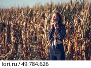 In a vast and vibrant cornfield, a young woman stands amidst towering stalks, savoring a delightful moment of peace and connection with nature, radiating a genuine sense of happiness and tranquility. A woman joyfully standing in a vast cornfield, embodying serene harmony with nature all around her. Стоковое фото, агентство Ingram Publishing / Фотобанк Лори