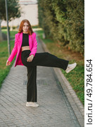 A stylish young woman confidently poses outdoors in a vibrant pink blazer and chic black pants, perfect for urban street style photography and showcasing modern fashion with bold colors and elegance. A Trendy Fashion Model is Posing Confidently in a Vibrant Blazer and Chic Fashionable Pants. Редакционное фото, агентство Ingram Publishing / Фотобанк Лори