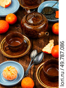 Fresh brewed spicy fruit tea with tangerines or mandarins on wooden rustic background.. Mandarin tea in glass teapot or kettle. Стоковое фото, агентство Ingram Publishing / Фотобанк Лори