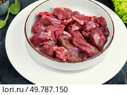 Raw venison slices arranged with fresh fragrant herbs.. Sliced raw venison deer meat for a stew. Стоковое фото, агентство Ingram Publishing / Фотобанк Лори