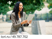 A cheerful woman is happily enjoying her tablet in a vibrant green outdoor setting, perfectly showcasing the blend of modern technology and leisurely enjoyment amidst natures beauty. A Joyful Woman Happily Engaging with Her Tablet While Enjoying the Outdoors in Nature. Стоковое фото, агентство Ingram Publishing / Фотобанк Лори