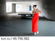 In a striking urban landscape, a graceful dancer enchants the audience while wearing a flowing red dress, performing beautifully amidst the minimalist architecture that frames the moment in time. Beautiful and elegant dance movement in unique urban environments that inspire thought. Стоковое фото, агентство Ingram Publishing / Фотобанк Лори