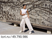 A talented dancer showcases an elegant and stunning pose in flowing attire, perfectly set against a beautifully textured wall, embodying the true essence of grace and dynamic movement in art. A dynamic dance pose against a vibrant wall backdrop, showcasing elegance and energy. Стоковое фото, агентство Ingram Publishing / Фотобанк Лори