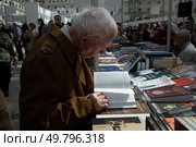 Международная ярмарка интеллектуальной литературы «non/fictioNвесна» в Гостином дворе. Пожилой мужчина читает книгу. (2023 год). Редакционное фото, фотограф Дмитрий Киселёв / Фотобанк Лори